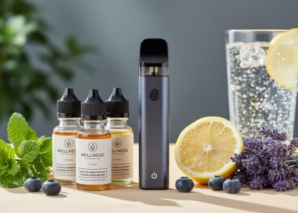 Close-up lifestyle photo of vape device and wellness e-liquid bottles on a wooden surface with mint, lavender, lemon, and blueberries in soft natural light.